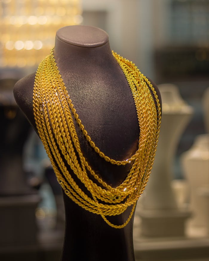 gallery-2 Luxurious gold necklace showcased on a mannequin in a jewelry store, highlighting elegance and style.