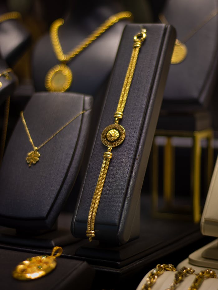 gallery-1 Luxurious gold jewelry elegantly displayed on black stands in a jewelry store.