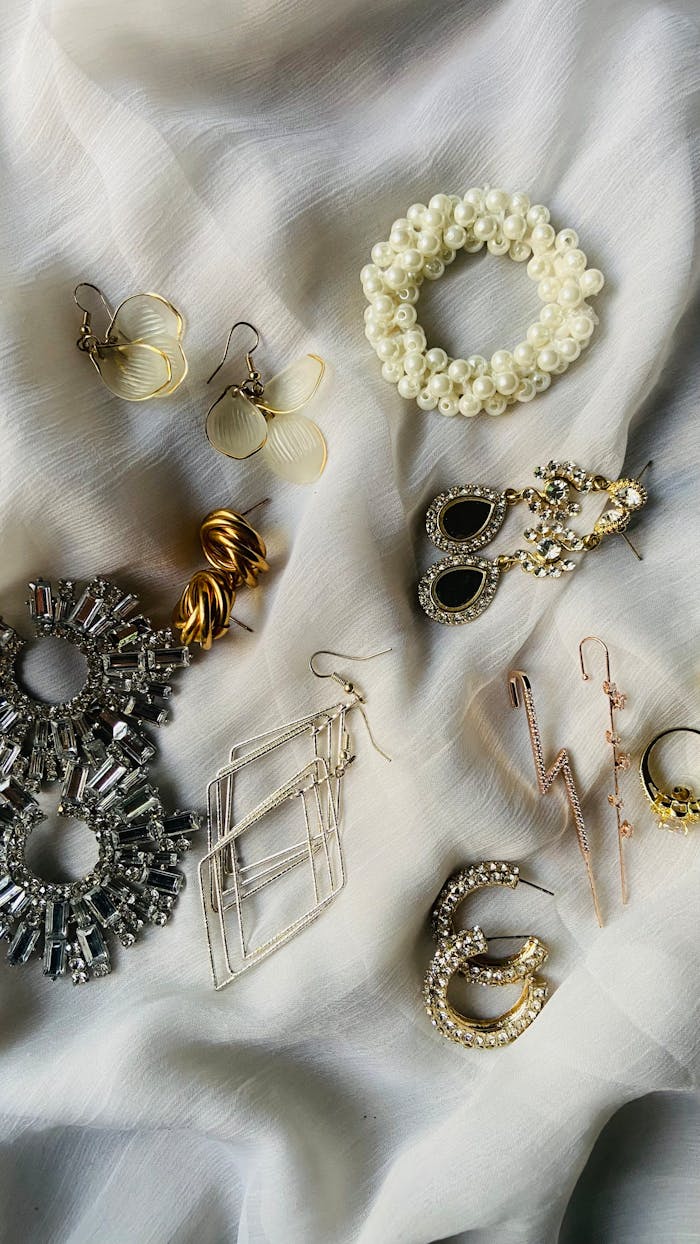 A stylish display of various earrings and jewelry pieces on a white fabric background.