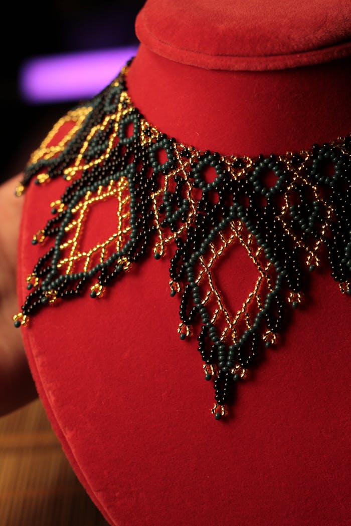 gallery-4 Intricate beaded necklace draped on a red velvet bust, showcasing exquisite craftsmanship.
